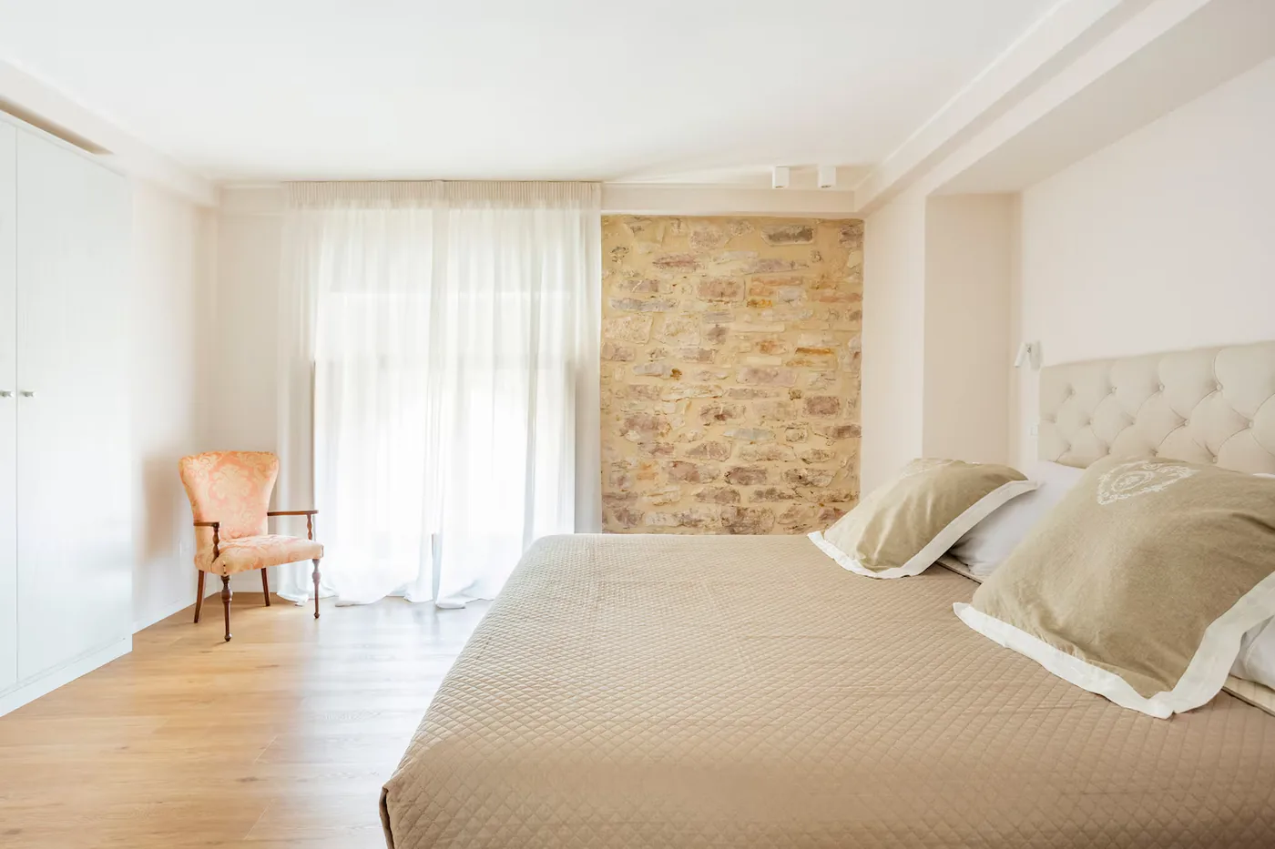 Camera del loft con parete in pietra rosa del Subasio e finestra