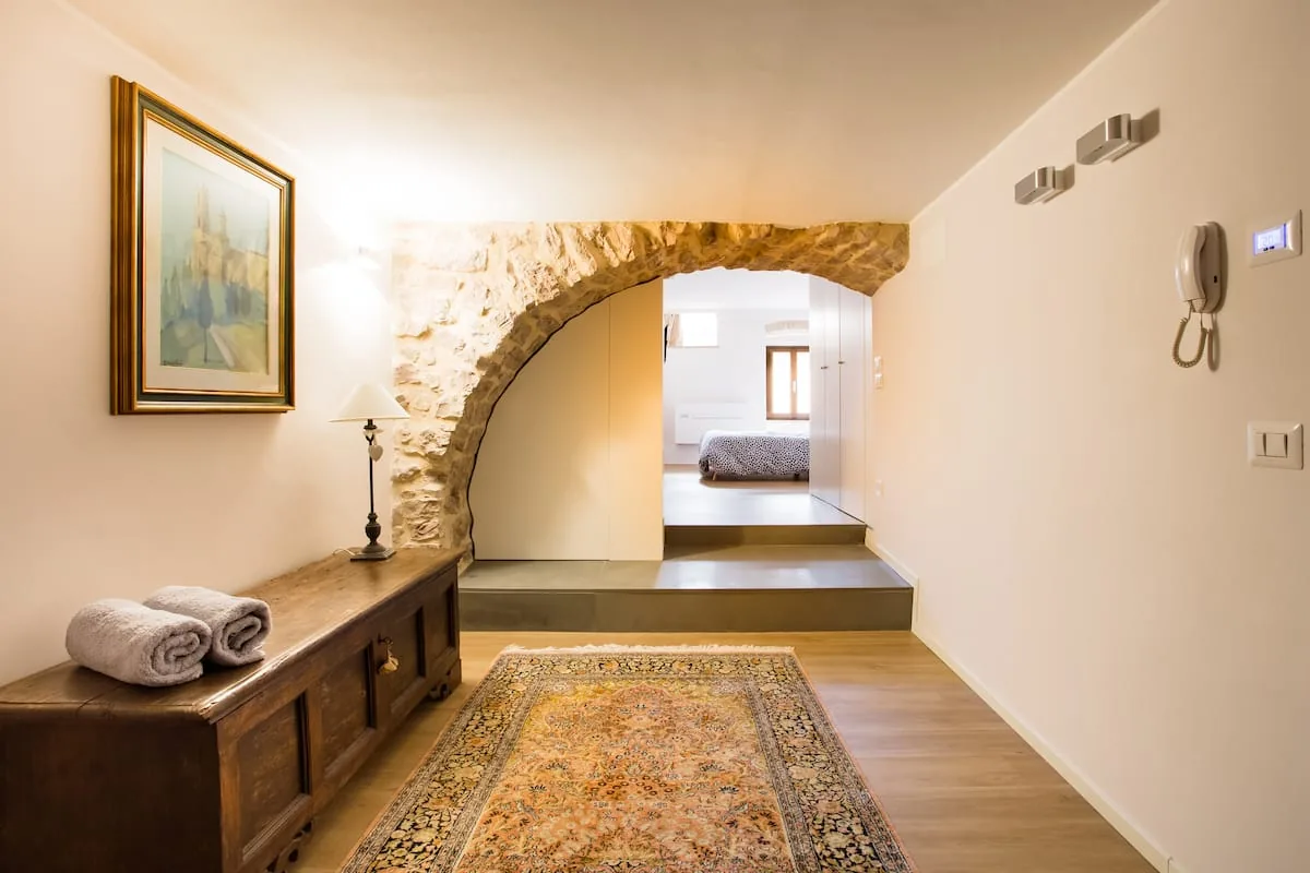 Ingresso con arco in pietra, tappeto e cassapanca antica