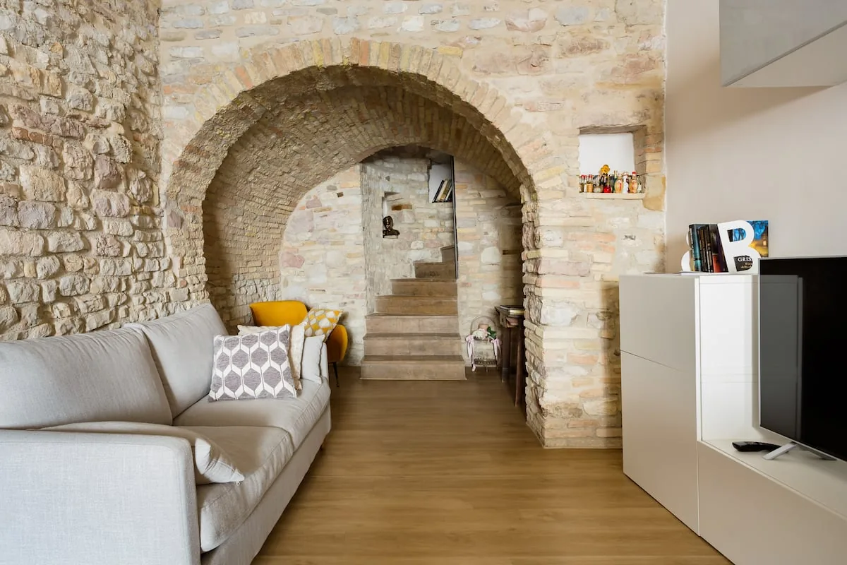 Sorella Luna boutique home: salone con grande arco in pietra e divano ad Assisi